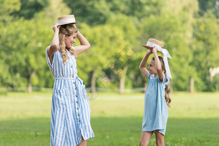 快乐的母亲和女儿假扮草帽在草坪图片