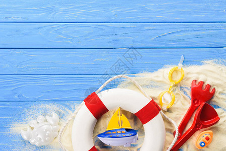 蓝色木制背景上的救生圈和玩具船图片