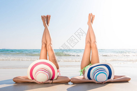 感比基尼身材的亚洲女穿着女帽躺在沙滩上图片