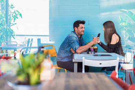 快乐的年轻情侣坐在餐厅里背景图片