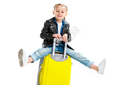 小旅游者坐在黄色轮式手提箱上图片