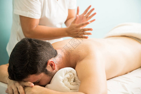 一名女治疗师在一家温泉疗养所使用显微按摩技术对一个男子的背图片