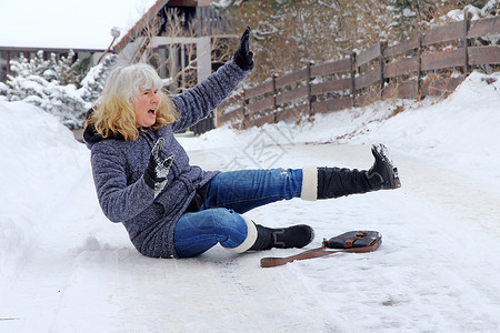 一名妇女滑倒在冬天的路上摔倒图片