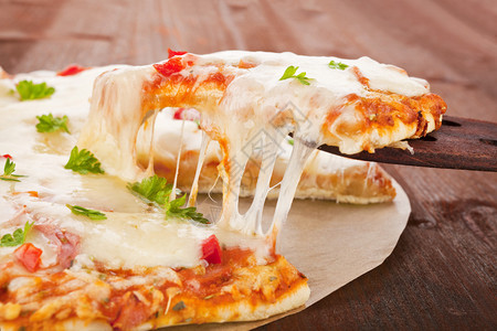 甜美的热披萨片配着融奶酪的木勺子精致图片