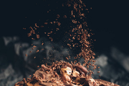 碎的巧克力片落在一块有坚果背景图片