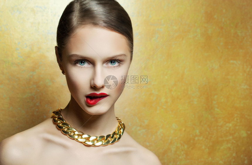 迷人感的年轻女人完美地和金项链相配在黄色背景上图片