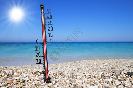 海滩上的温度计显示高温背景图片