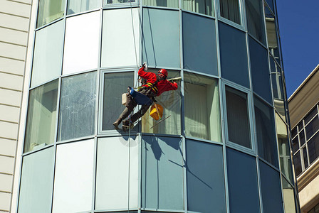 工人戴头盔从外面清洗高楼大的窗户背景图片