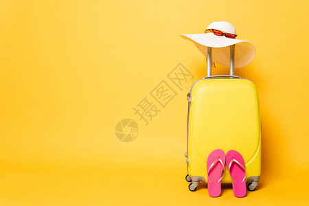 黄色旅行袋上面有翻滚太阳帽和太阳墨镜图片