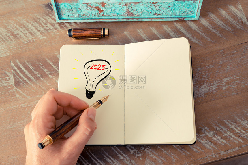 一个女人用钢笔在记本上画一个灯泡的复古效果和色调图像2025年代表聪明想法和商业概念的标志图片