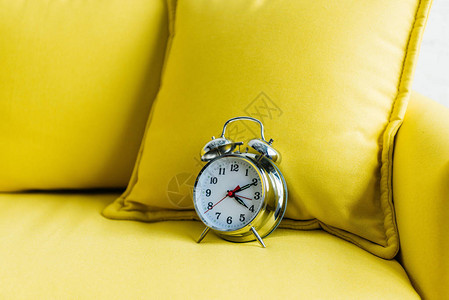 黄色沙发上金属闹钟的近景背景图片