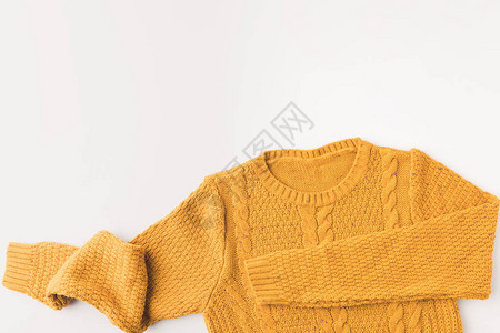 针织暖黄色毛衣的顶部视图白色隔离背景图片