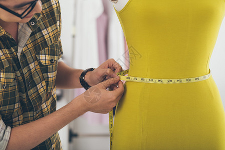 测量人体模型腰部的男裁缝图片
