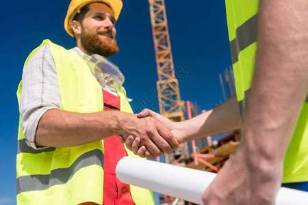 欢快的建筑工人与建筑师或工头握手图片