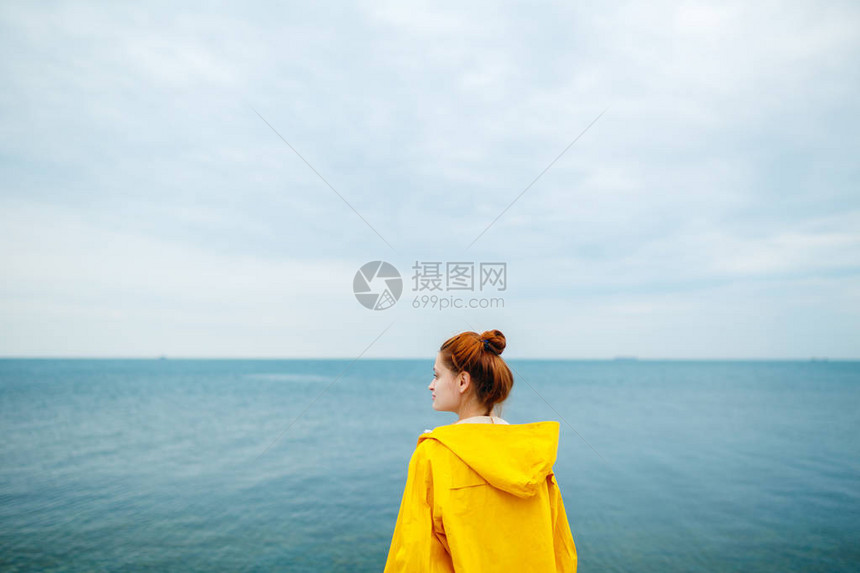 黄雨衣的红发女人背影看着蓝海的背图片
