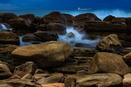 海滩上大岩石海浪不断涌入船图片