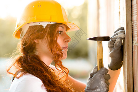 戴头盔的女瓦工用锤子敲钉子图片