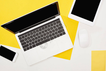 笔记本电脑智能手机带空白屏幕的数字平板电脑和黄色和白色背景的电脑鼠图片