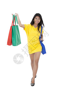 一名穿着黄色礼服的女士在拿着购物袋时笑图片