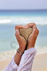 大海背景下女人手中沙子的心图片