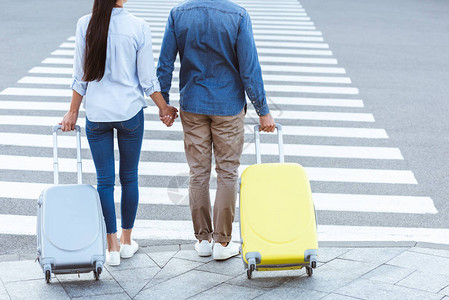 一对夫妇旅行者通过行人手牵和拉行李的作物风景图片