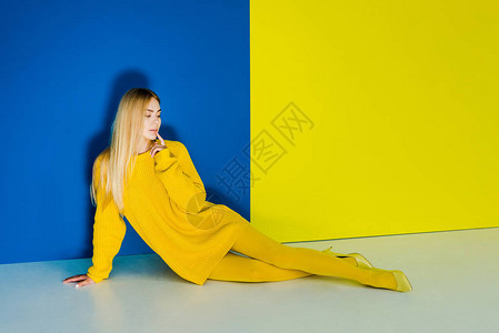 穿着黄色衣服的漂亮年轻女孩躺在蓝色和黄色图片