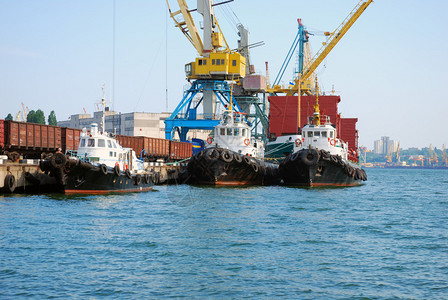 海港三艘拖船轮船和起重机图片