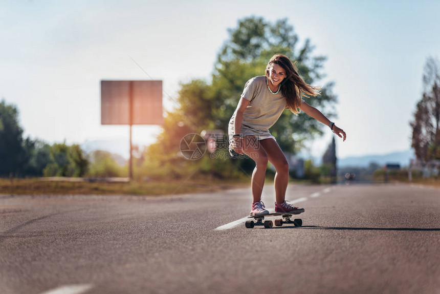 女生在道路上玩滑板图片