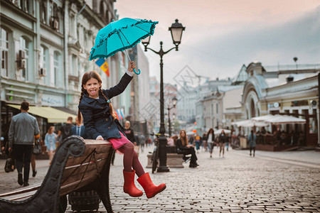 小女孩在莫斯科的长椅上撑着蓝色雨伞图片
