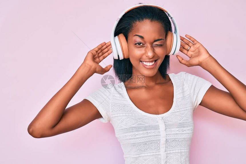 年轻非裔美国妇女用耳机收听音乐图片