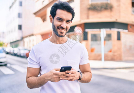 年轻的西班牙年轻人在城里用智能手机微笑图片