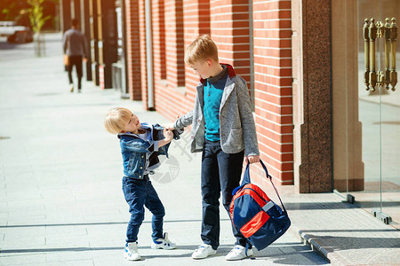 背着书包去上学的童户外时尚的兄弟回到学校的概念朋友童年和教育小学街头图片