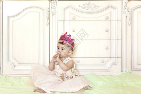 第一个生日快乐的小女孩戴着皇冠庆祝她的第一个生日聚会作为公主打扮的一图片