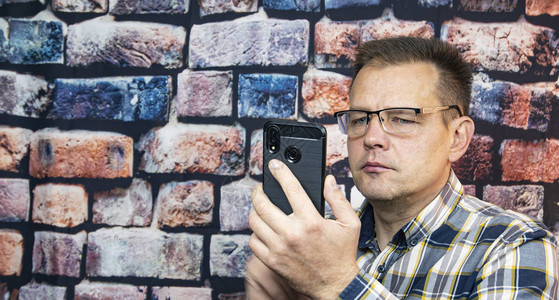 一个戴眼镜的人手里拿着手机人技图片