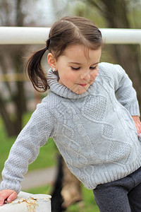 穿着毛衣的可爱小女孩单手撑在铁箱上图片
