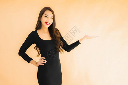 纯色背景前单手叉腰展示某物的亚洲女性图片