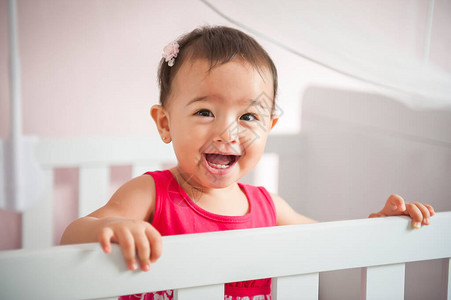 美丽的亚洲女孩在婴儿床里微笑和玩耍背景图片