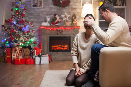 怀着眼罩的女人在圣诞节的一天里等待从丈夫那里收到礼物图片
