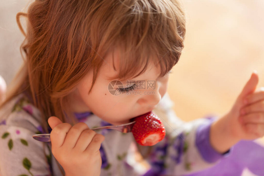 孩子在家里穿着睡衣吃早饭后吃草莓图片