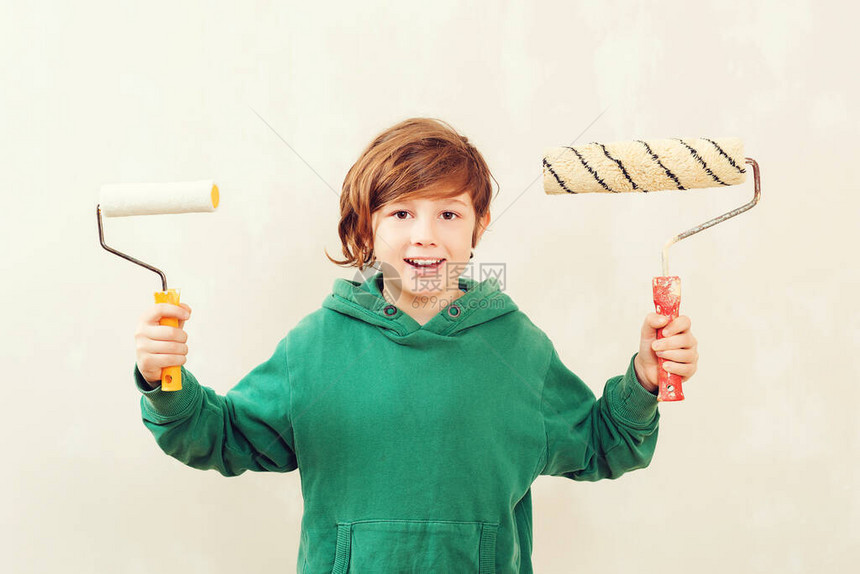 画辊的可爱男孩家居装修概念儿子帮助父母粉刷墙壁男孩用滚筒粉刷墙壁图片
