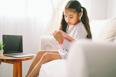 快乐的孩子在家里客厅的桌子上看书的亚洲小女孩图片