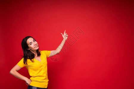 快乐的年轻成功女子用红背景将手指向图片