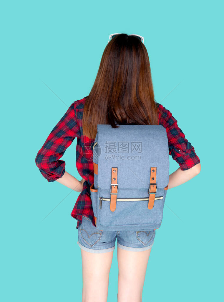 美丽的年轻亚洲女背着包旅行的背影与蓝色背景隔离图片