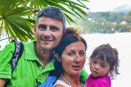 三个人幸福的家庭在美丽的海滩图片