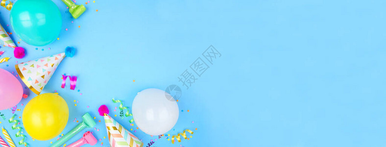 蓝色背景上带有角边框的生日派对横幅五彩纸屑气球派对帽和彩带的俯视图片