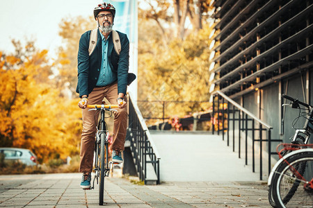 一个英俊的休闲中年商人骑自行车去办公室他正在办公图片