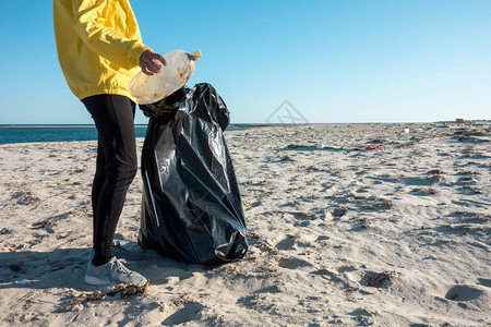 女人捡垃圾和塑料用垃圾袋清洁海滩反对气候变化和海洋污染的背景图片