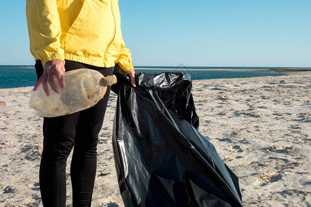 女人捡垃圾和塑料用垃圾袋清洁海滩反对气候变化和海洋污染的背景图片