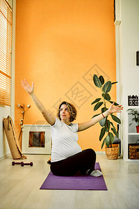 坐在公寓垫子上做瑜伽的中年孕妇瑜伽早图片