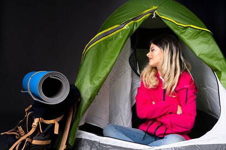 住在露营绿色帐篷中的少女在黑色背景背景图片